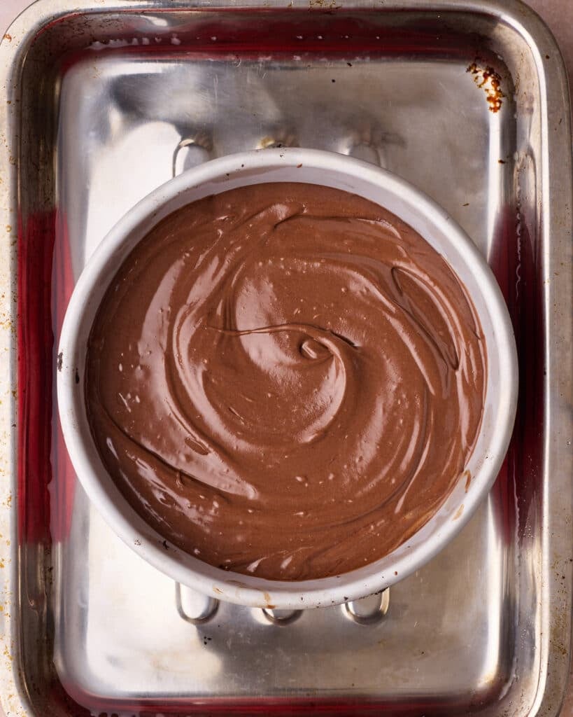 Chocolate cheesecake sitting in a water bath, ready to be baked.