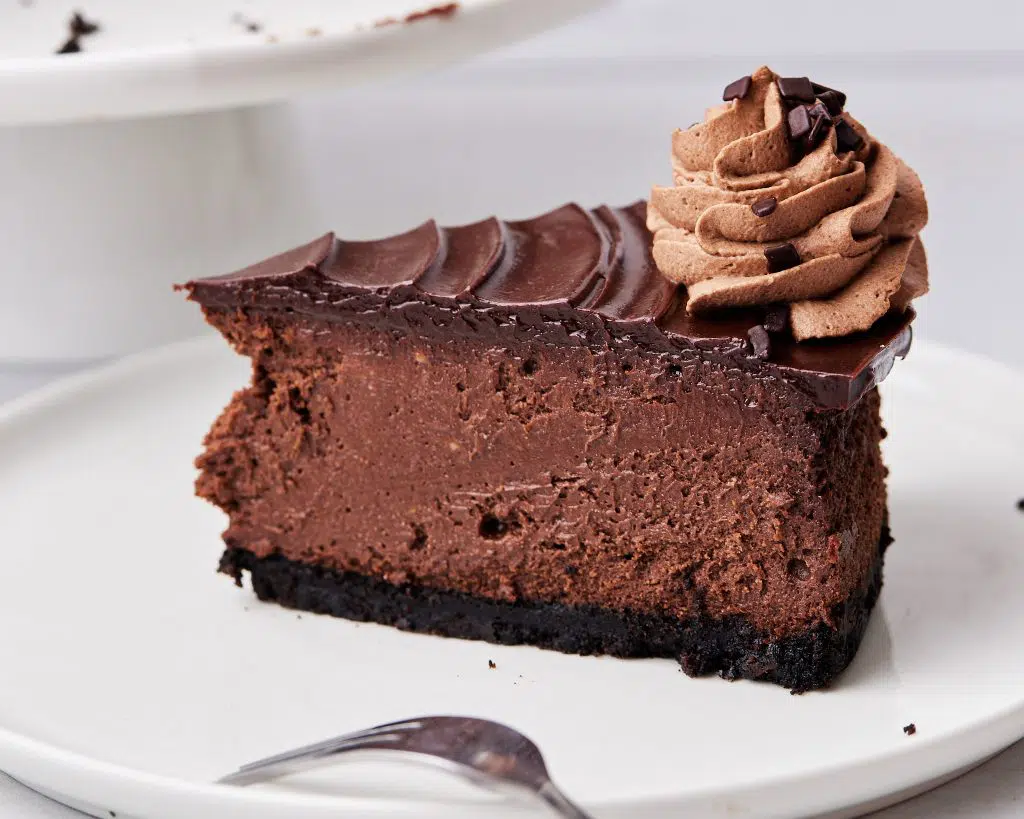 slice of chocolate cheesecake with chocolate ganache and chocolate whipped cream