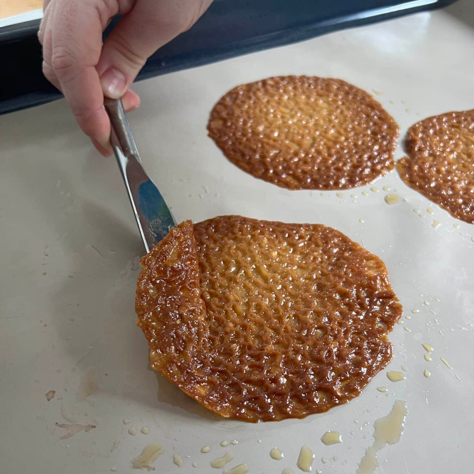 Lifting a lace snap off of the baking sheet with a knife.