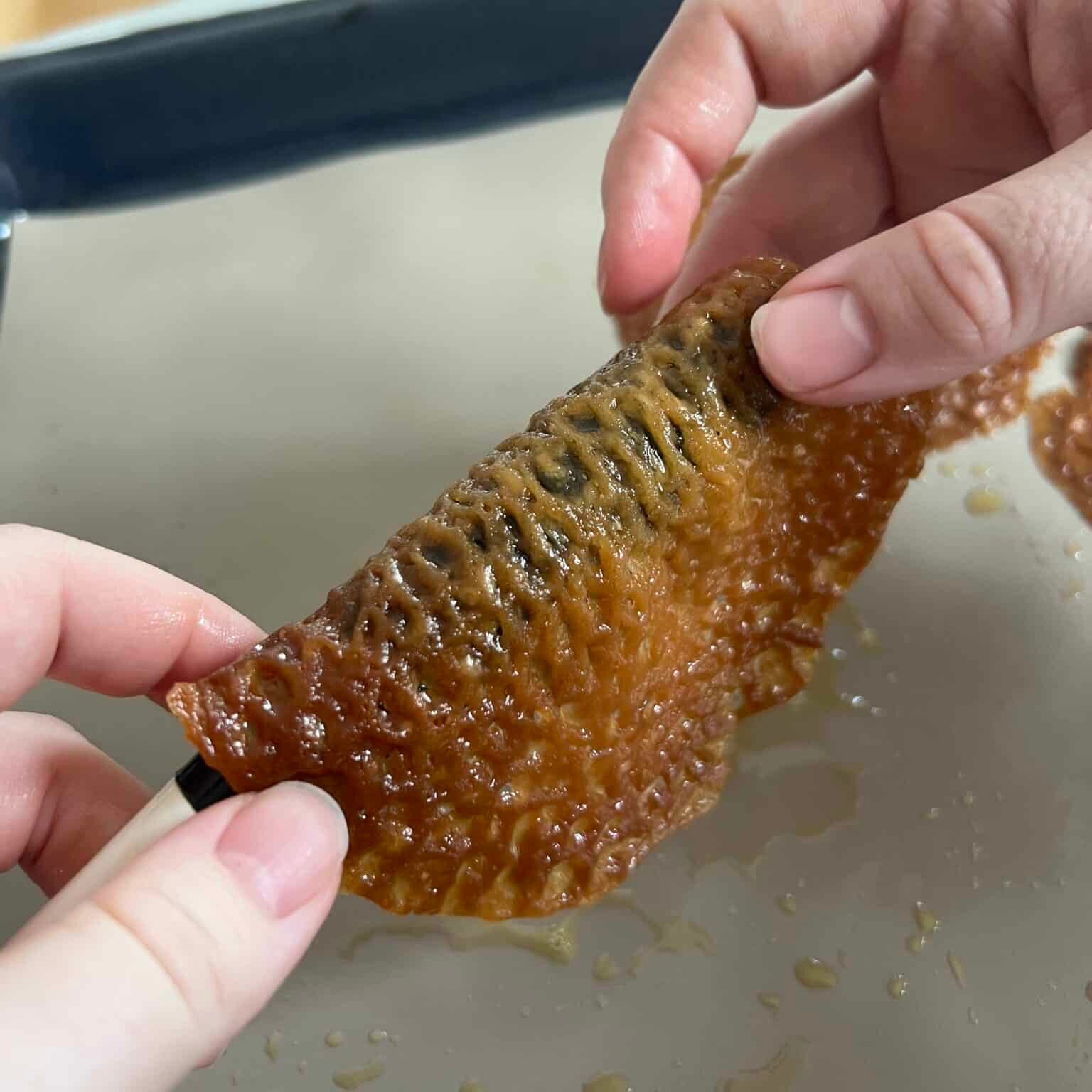 Wrapping a lace cookie around a thick spoon handle to make brandy snaps.
