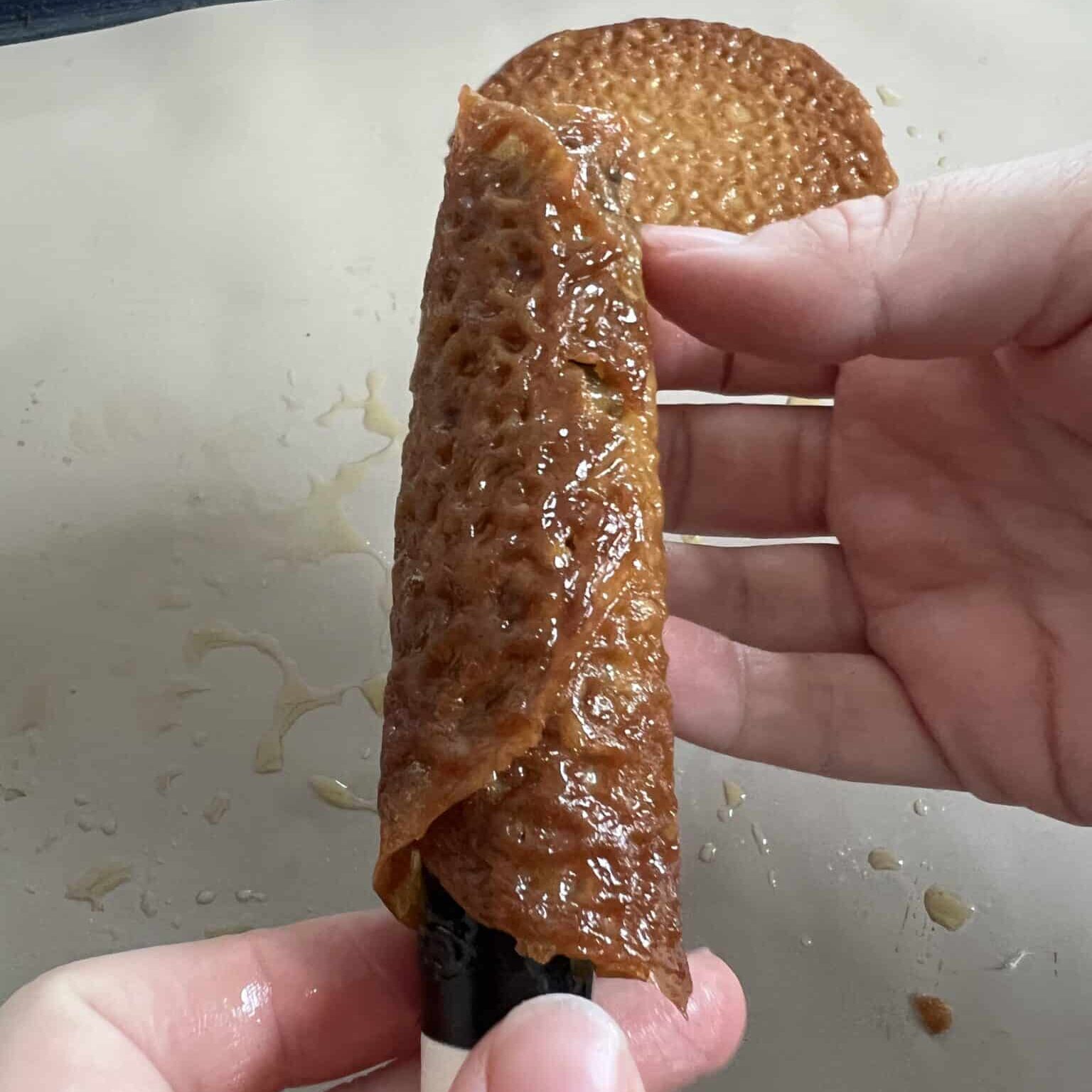 Brandy snap being shaped on a thick spoon handle.