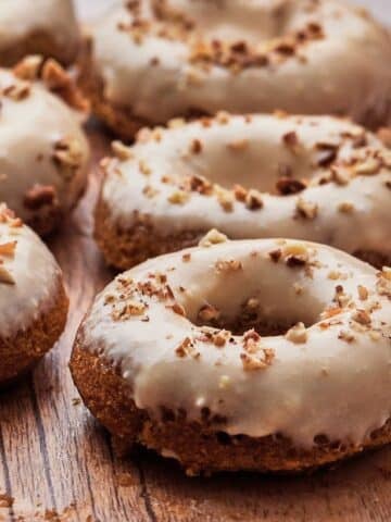 Pumpkin spiced donuts with a maple cream cheese icing and a sprinkling of pecans on top.