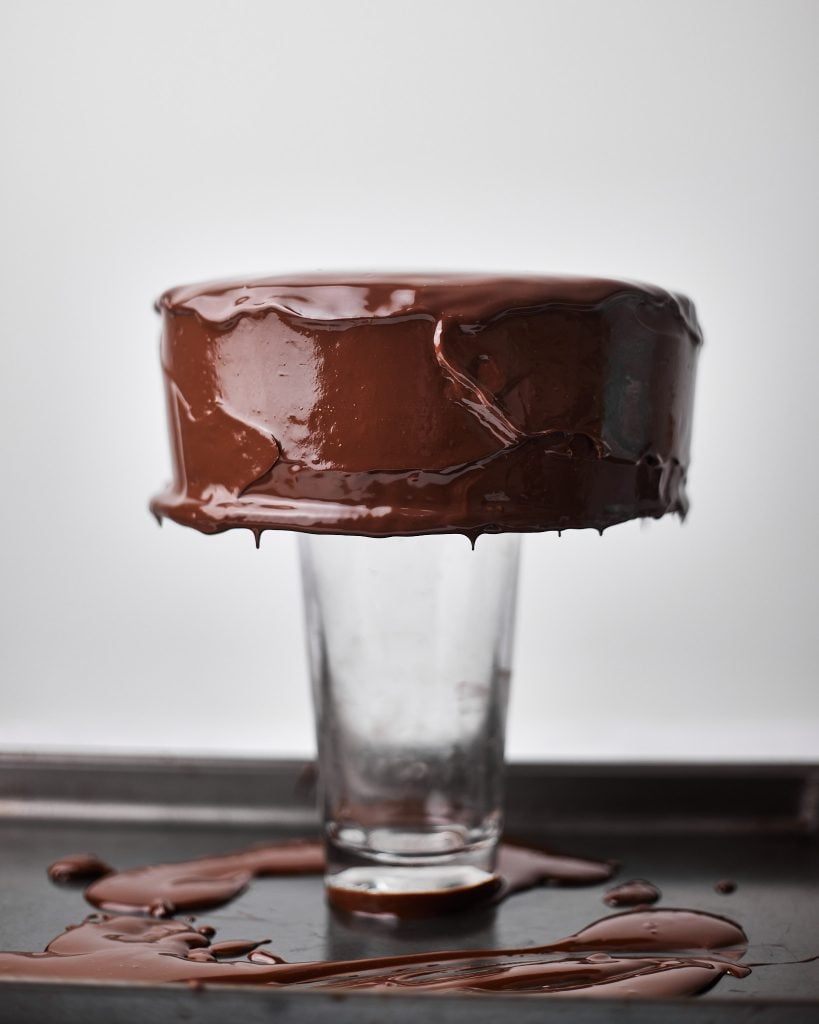 chocolate ganache being poured over a cake