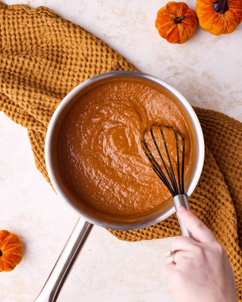 Whisking pumpkin curd in a saucepan over medium heat.