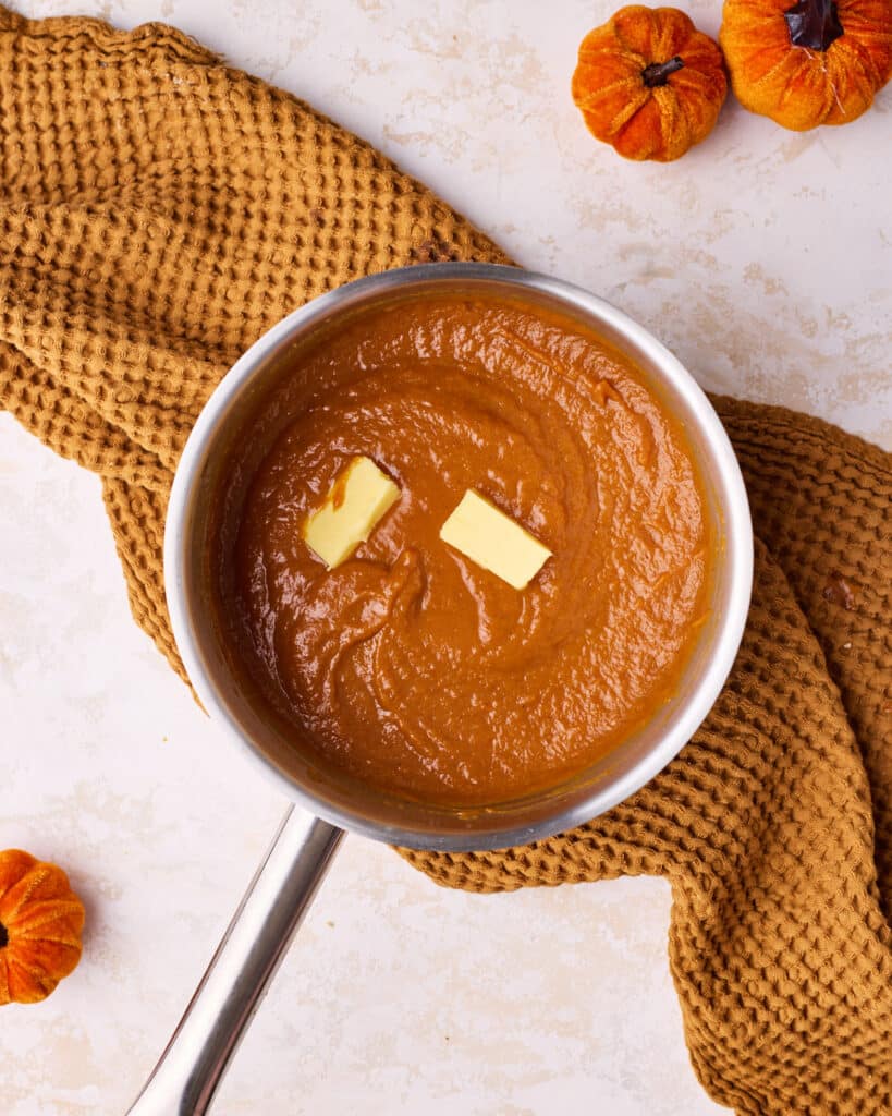 Adding butter to pumpkin mixture to make pumpkin curd.