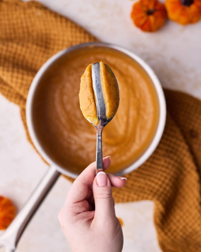 Testing pumpkin curd to see if it's ready by drawing a line in it on the back of a spoon.