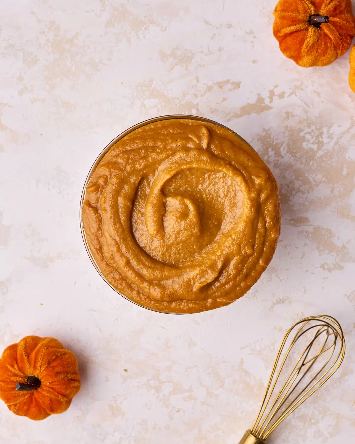 Pumpkin curd in a glass bowl with a swirl shape on top.
