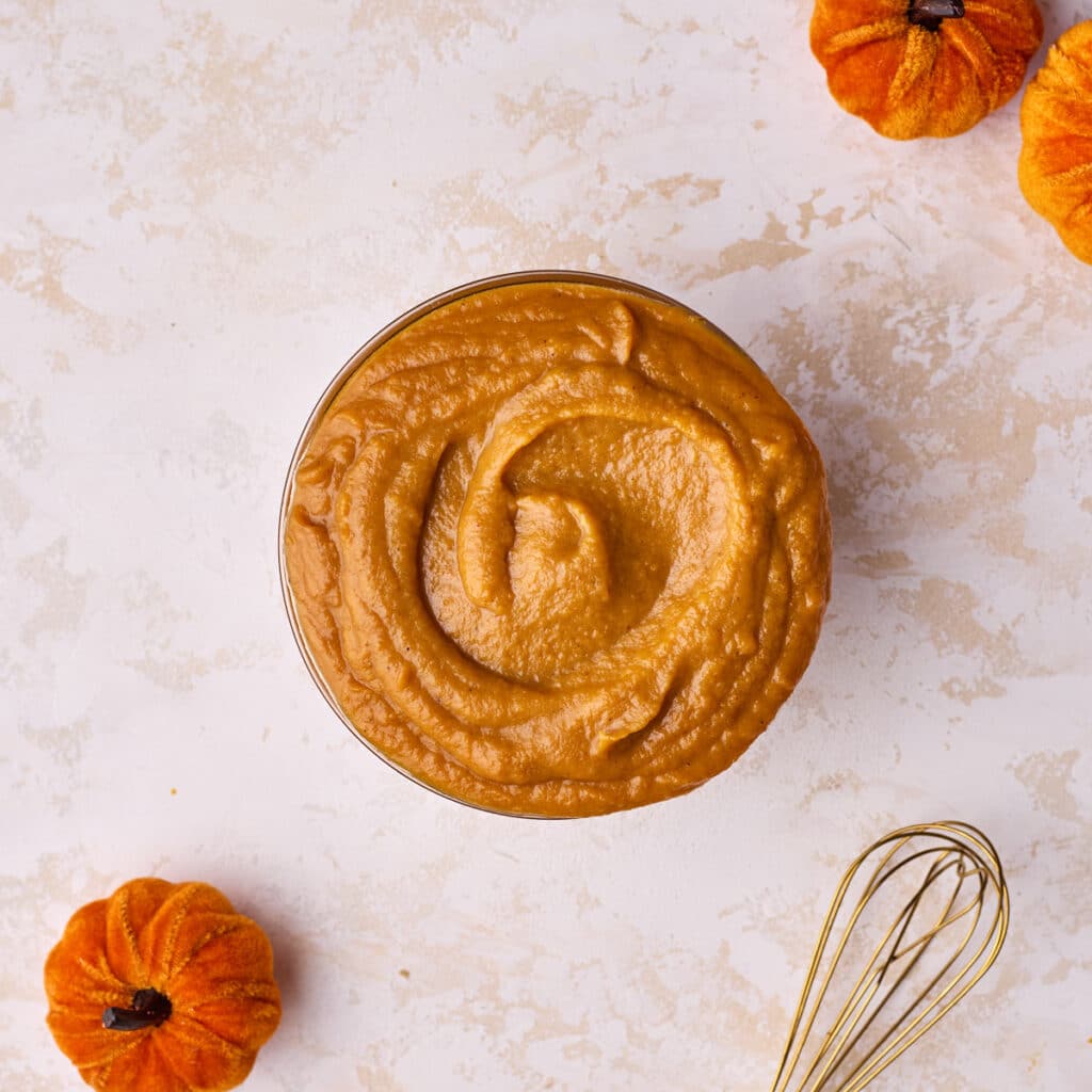 Pumpkin curd in a glass bowl with a swirl shape on top.