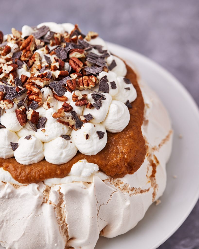 top of pumpkin pavlova with chopped pecans and chocolate shavings