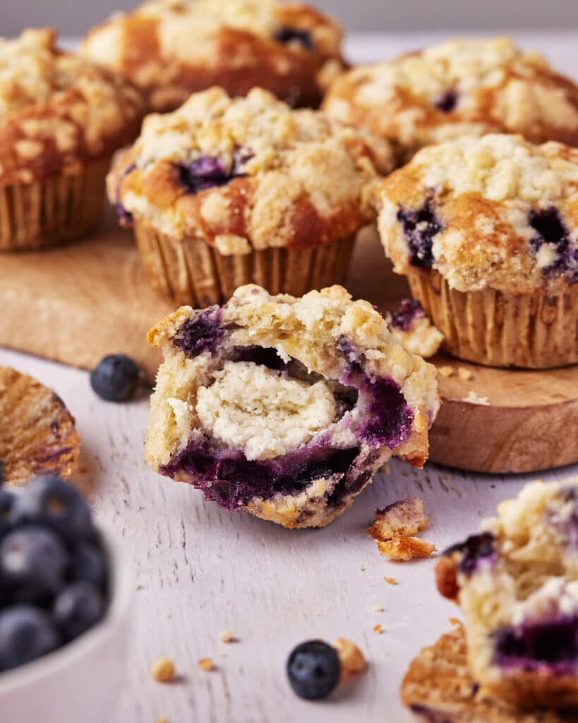 blueberry muffin bitten into to reveal a creamy cheesecake filling