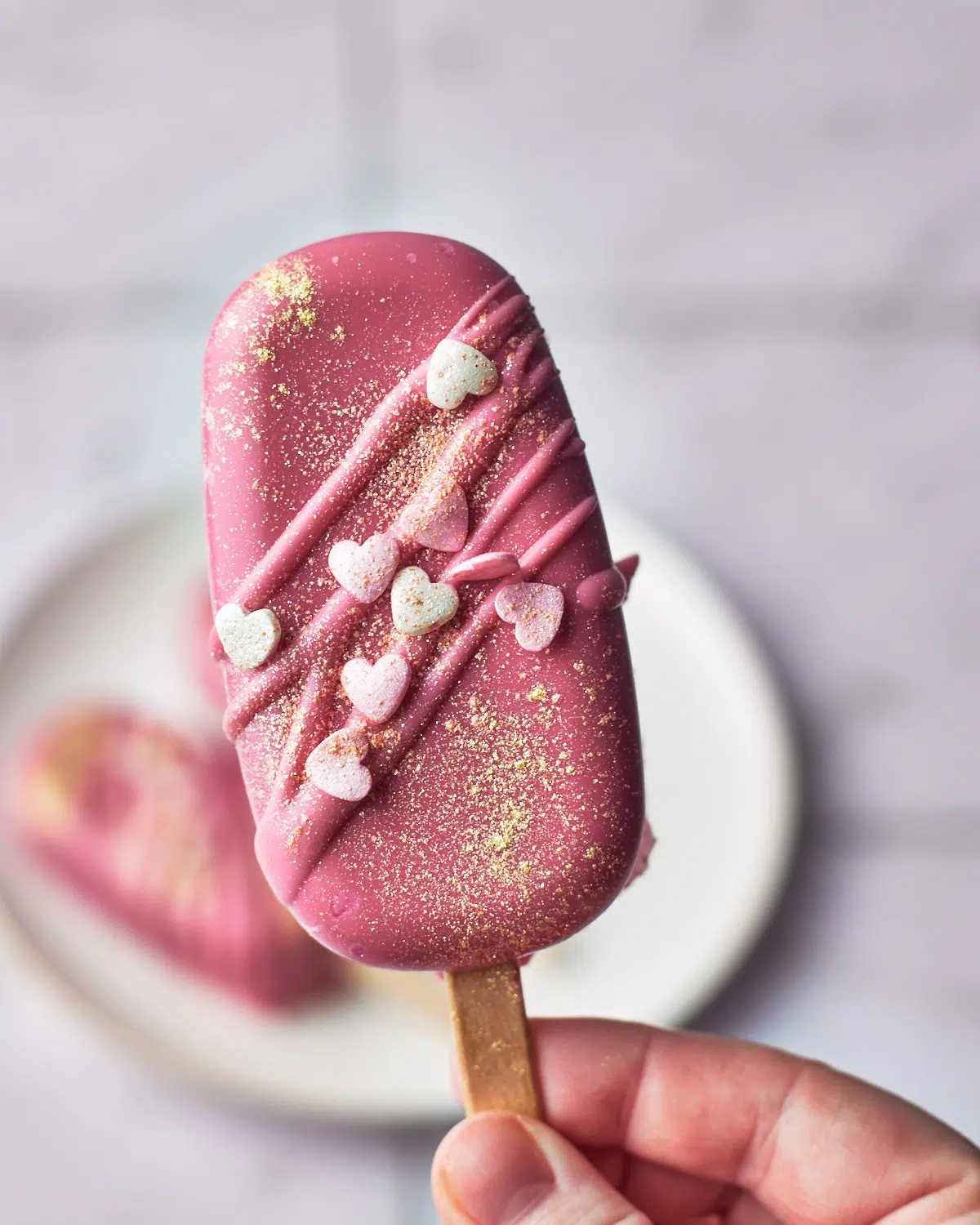 valentines cakesicle in pink candy melts with heart sprinkles
