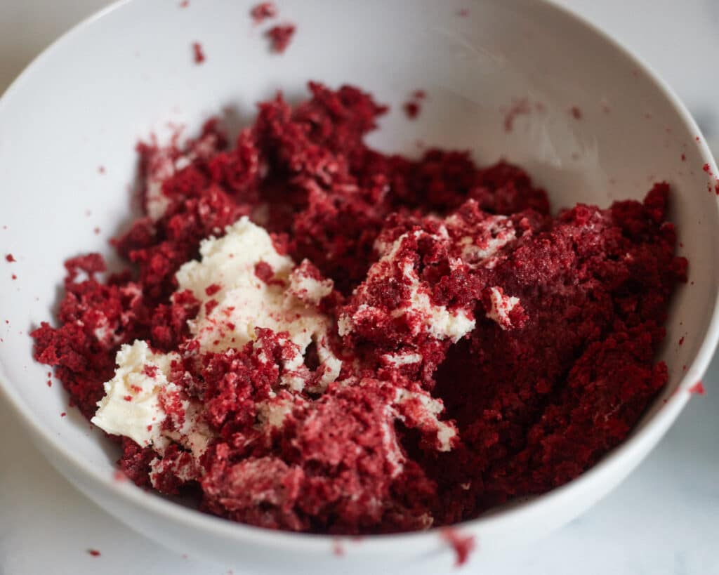 red velvet crumbs being mixed with cream cheese frosting for cakesicles