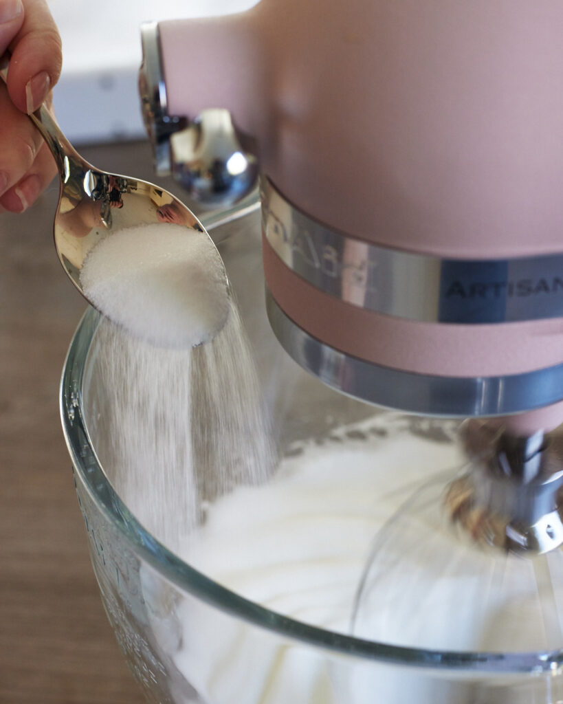 process shot of adding sugar to egg whites to make meringue
