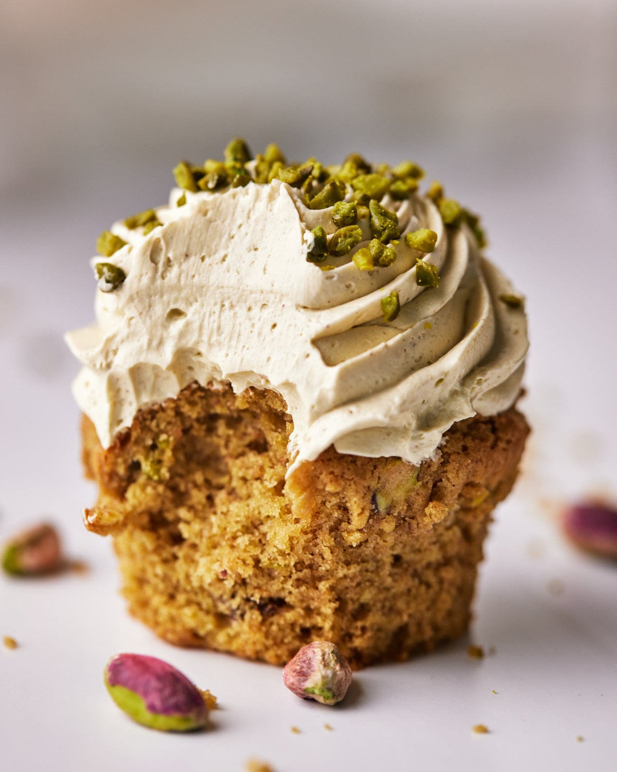 pistachio cupcakes with italian meringue buttercream with a bite taken out of it