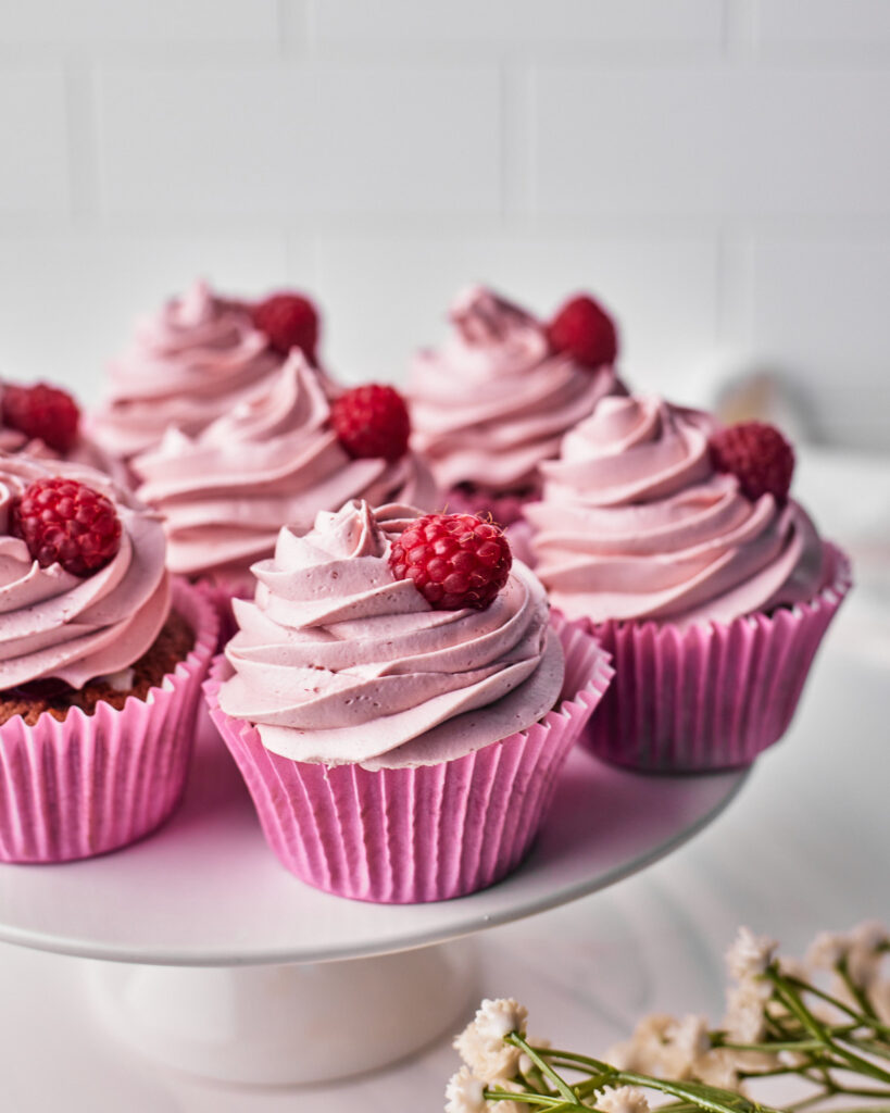 six raspberry cupcakes on a cake stand.