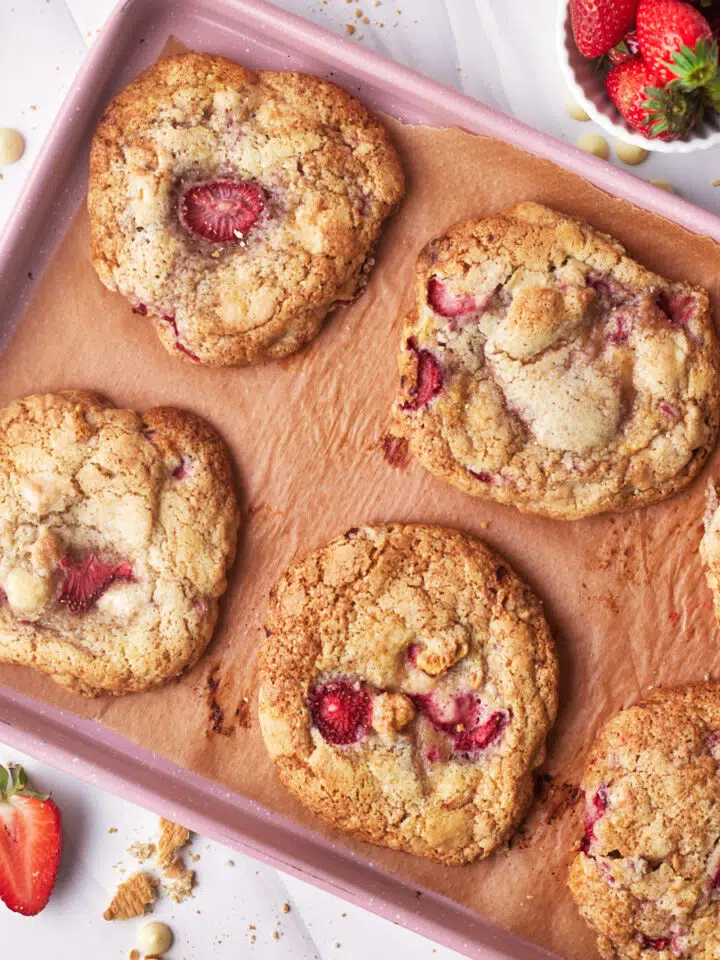 strawberry cheesecake stuffed cookies from above on a pink cookie sheet.