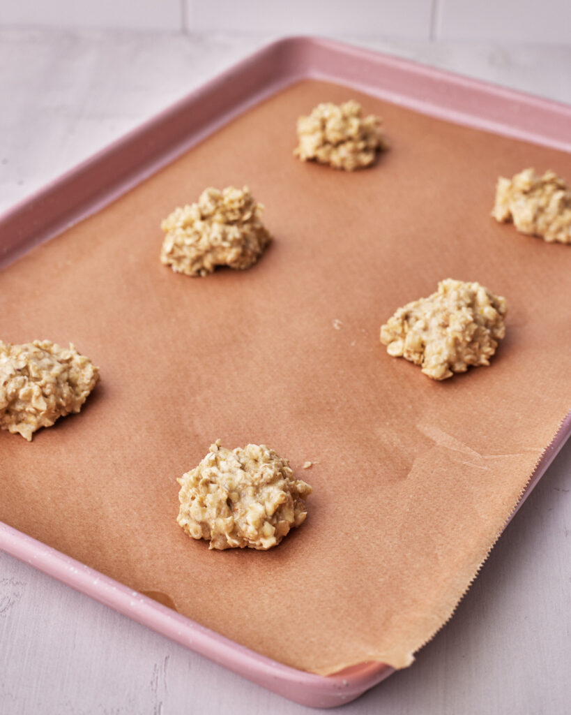 dollops of oatmeal cookie dough on a cookie sheet, ready to be baked. 
