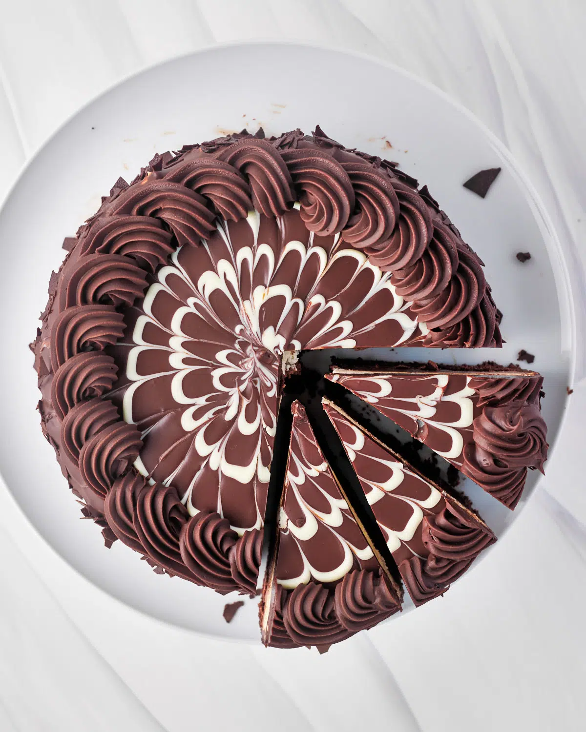 black tie mousse cake from above with three slices cut out of it. White chocolate feathering on top of chocolate ganache.