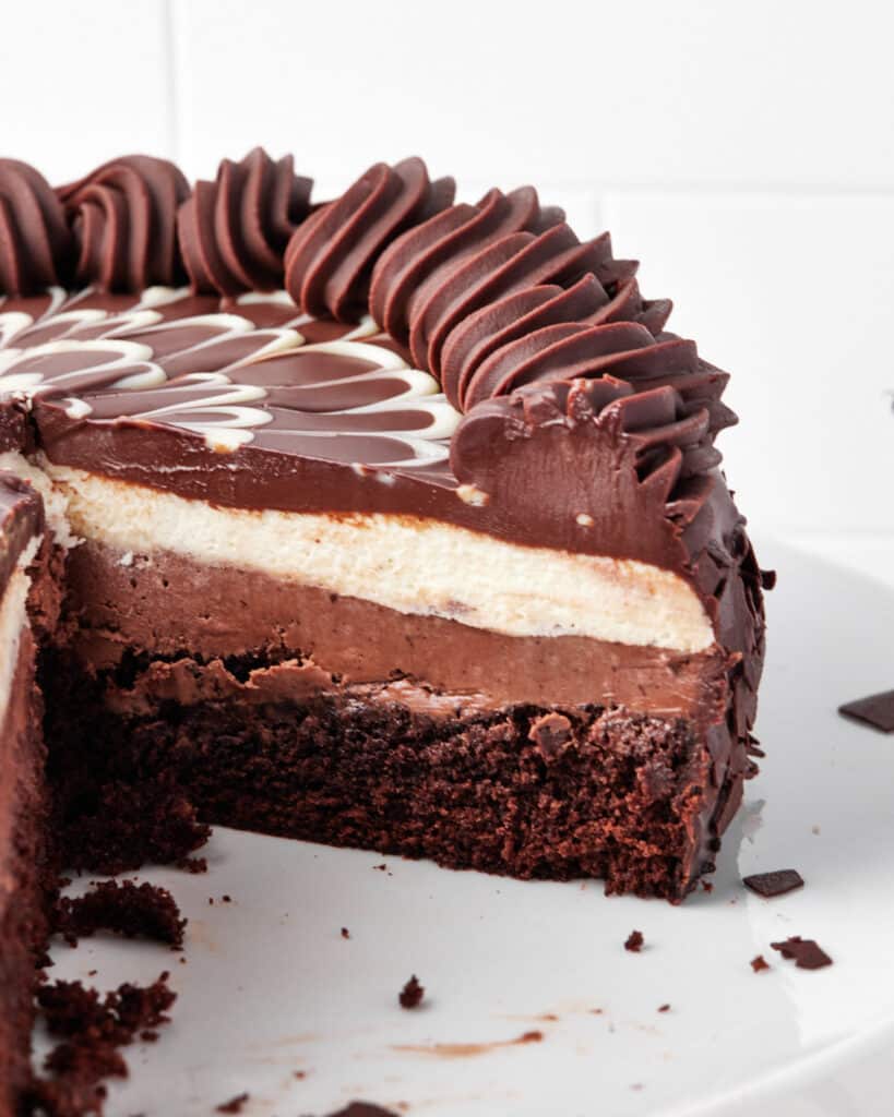 Black tie mousse cake with a big slice taken out of it to reveal four layers of chocolate.