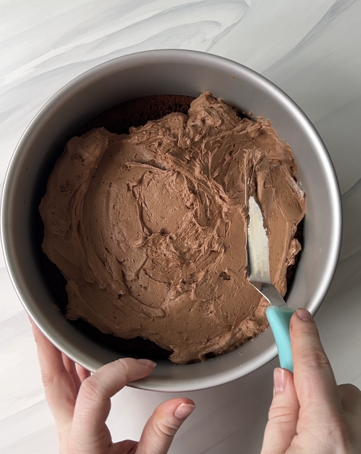 Chocolate cheesecake being spread onto chocolate cake for black tie mousse cake.