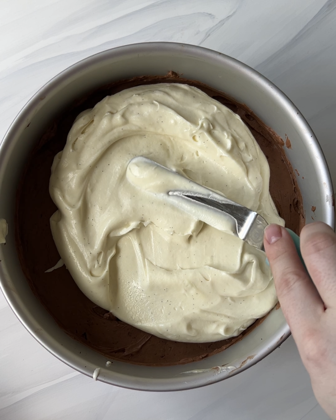 White Chocolate mousse being added as the third layer in black tie mousse cake.
