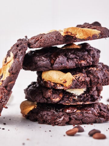stack of super thick gooey triple chocolate marshmallow cookies.