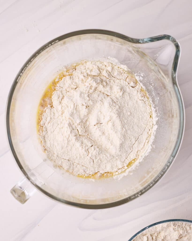 Adding flour to wet ingredients to make homemade donuts.  