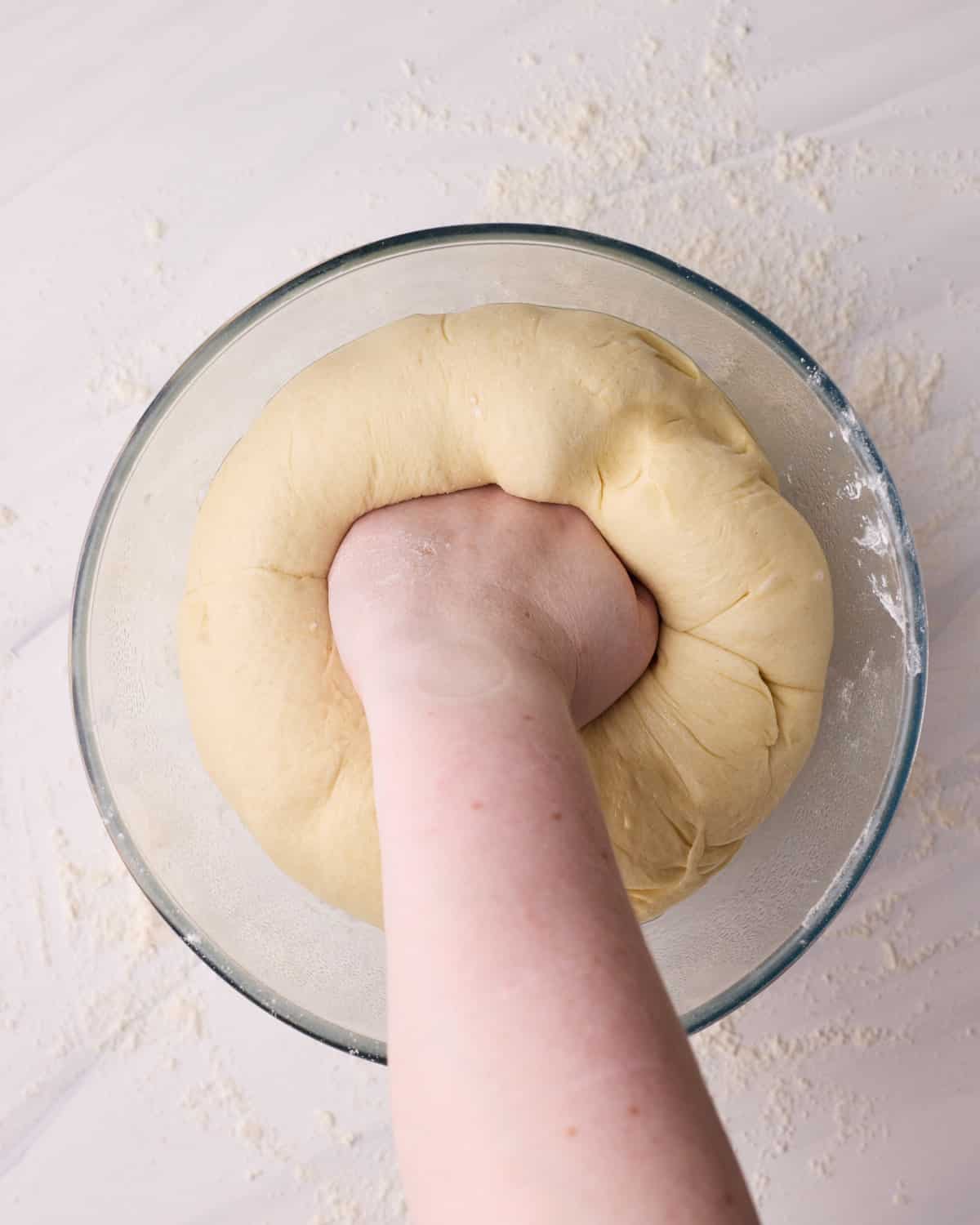 Punching excess air out of yeast donut dough after first proof.