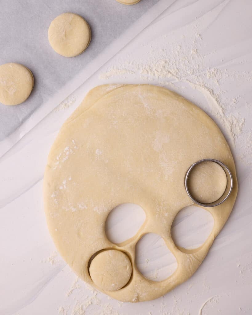 Cutting rounds out of yeasted dough to make donuts.