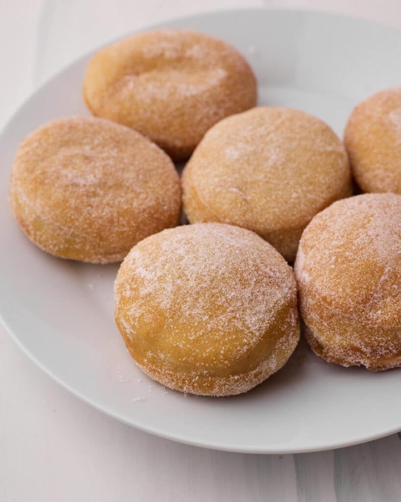 Fried donuts on a plate, coated in sugar.