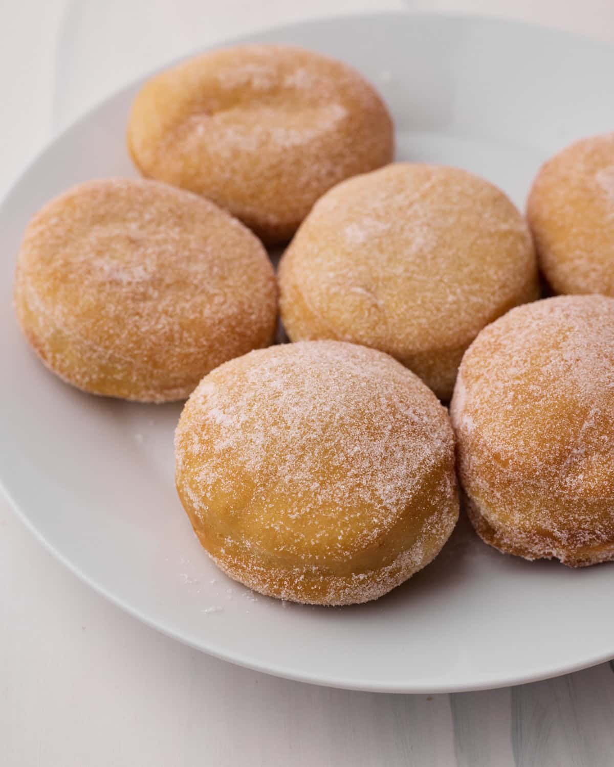 Fried donuts on a plate, coated in sugar.