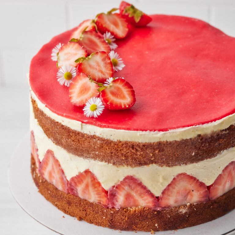 Fraisier cake from the side with fresh strawberries showing on side of the cake.