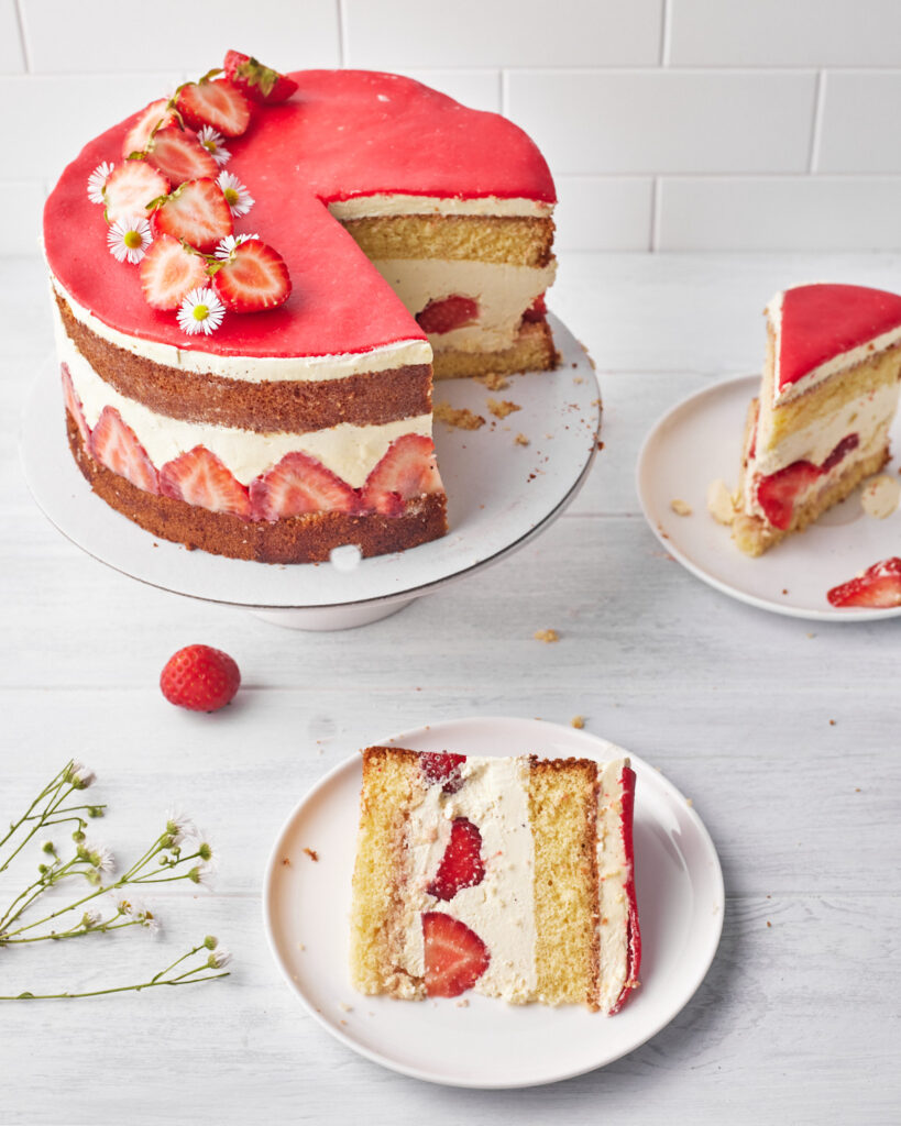 fraisier (french strawberry cake) with two slices taken out of it on plates.