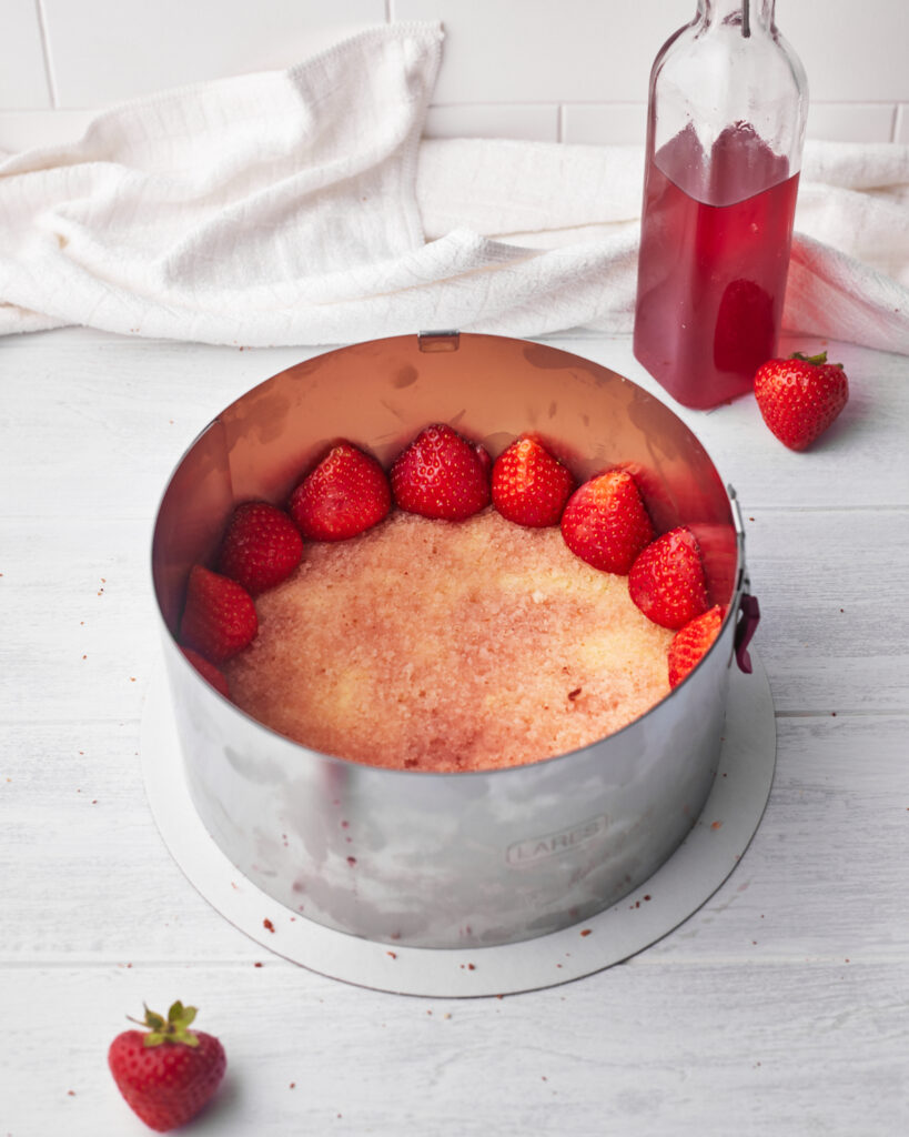 strawberries lining the outside of a cake ring to make fraisier cake. 