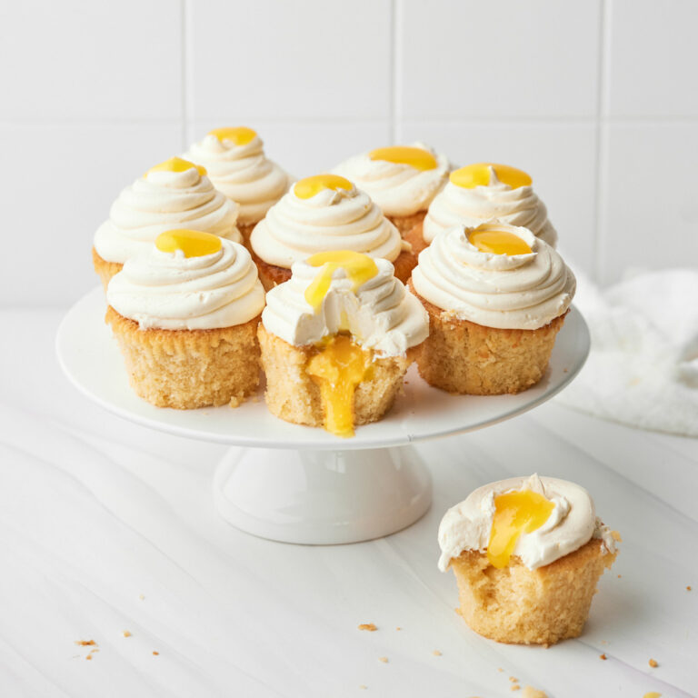 mango cupcakes on a cake stand with mango coulis oozing out the middle.