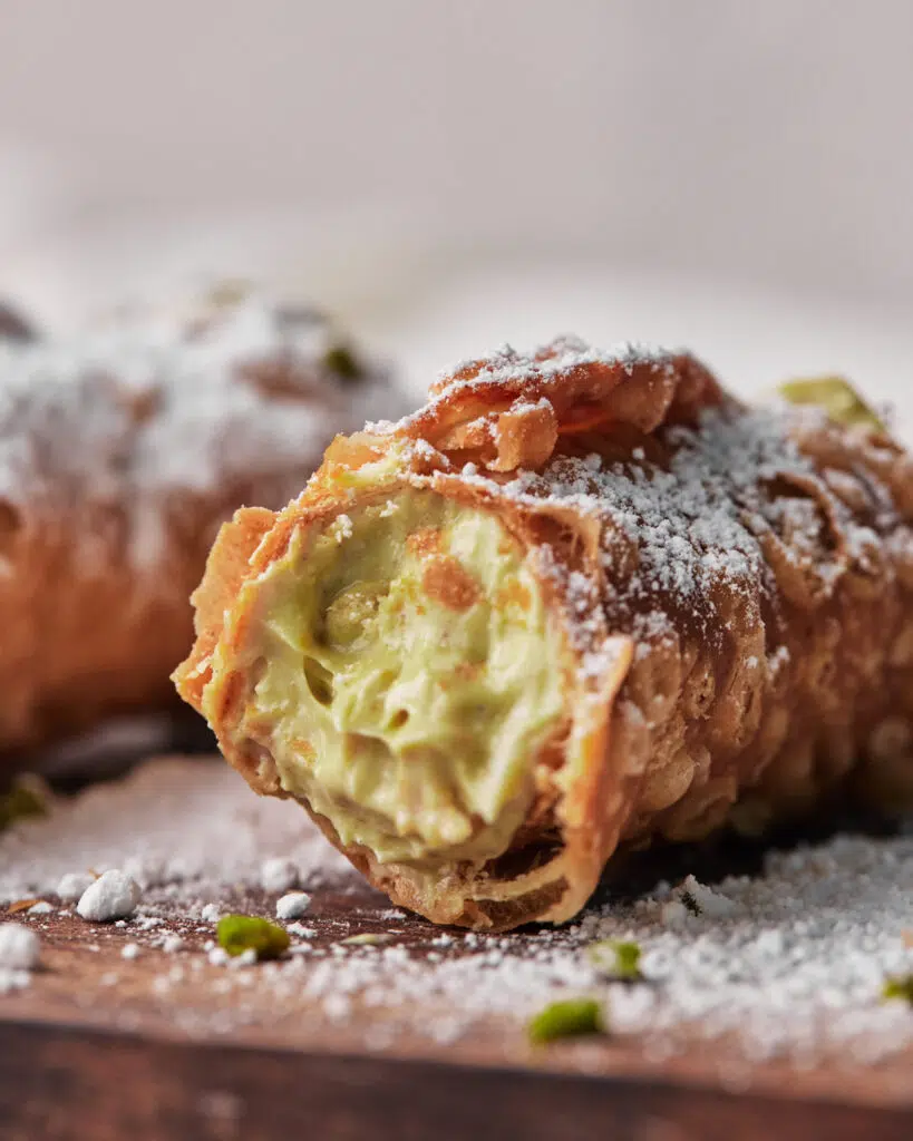 close up of pistachio cannoli with bite taken out.