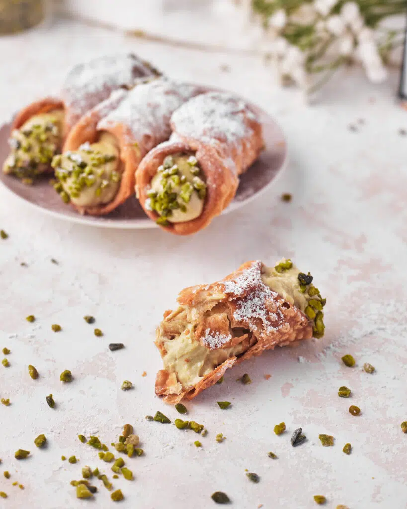 pistachio cannoli with a bite taken out to show flaky shell. 