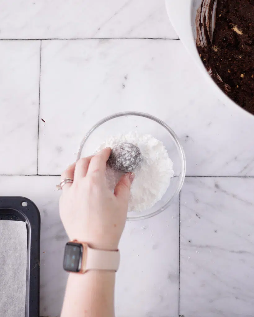 chocolate ball being rolled in powdered sugar for scottish truffles.