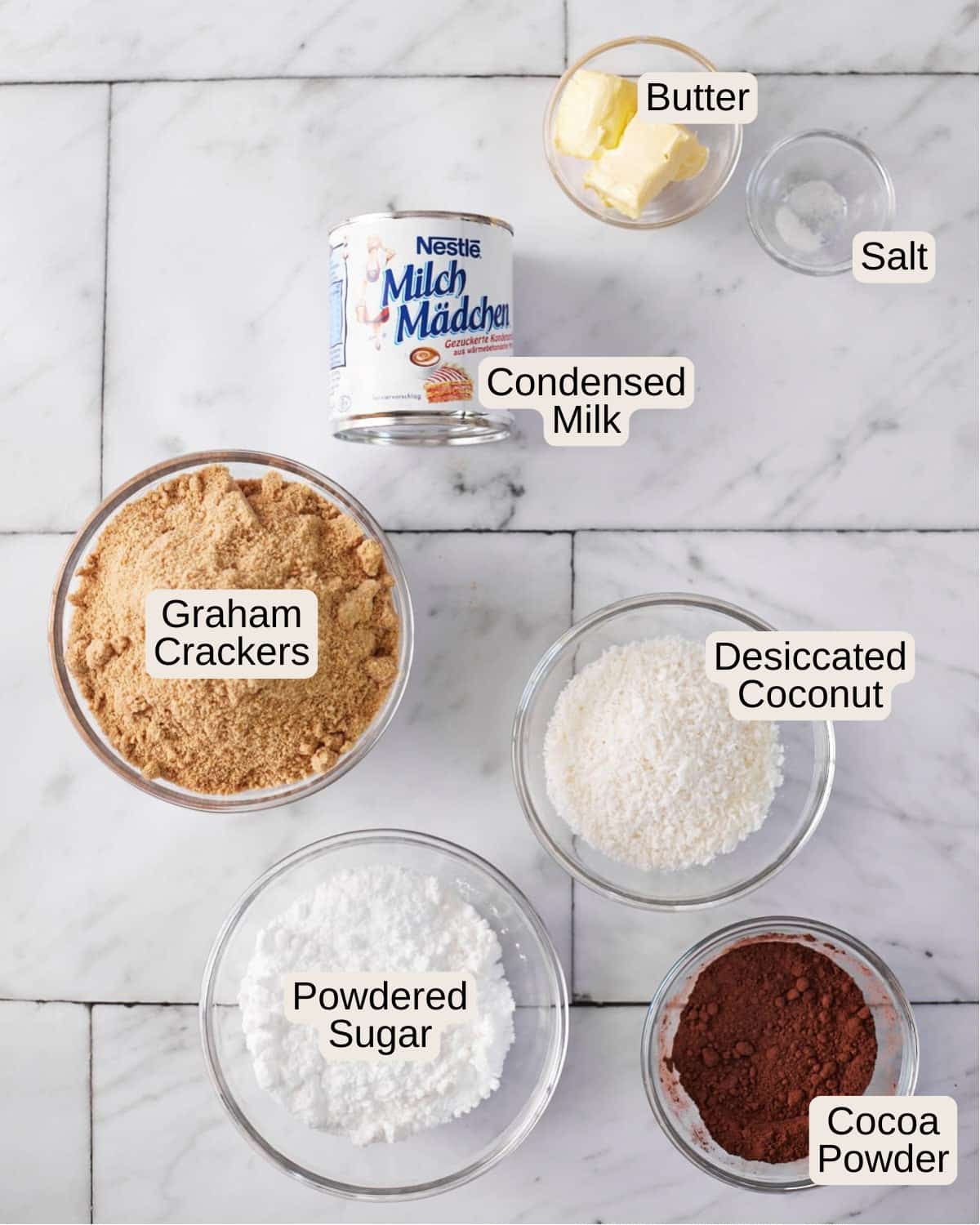 Ingredients for Chocolate Balls, including butter, salt, condensed milk, graham crackers, desiccated coconut, powdered sugar, cocoa powder.