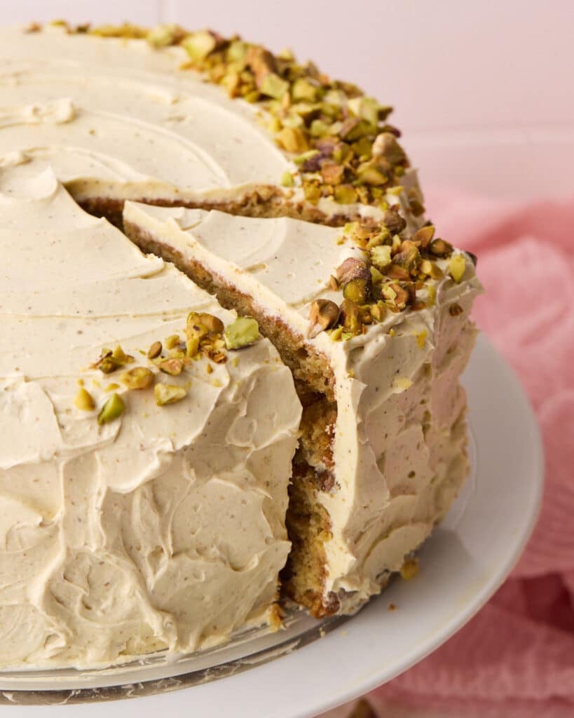 pistachio cake with pistachio Italian meringue buttercream, a slice is being taken out of it.