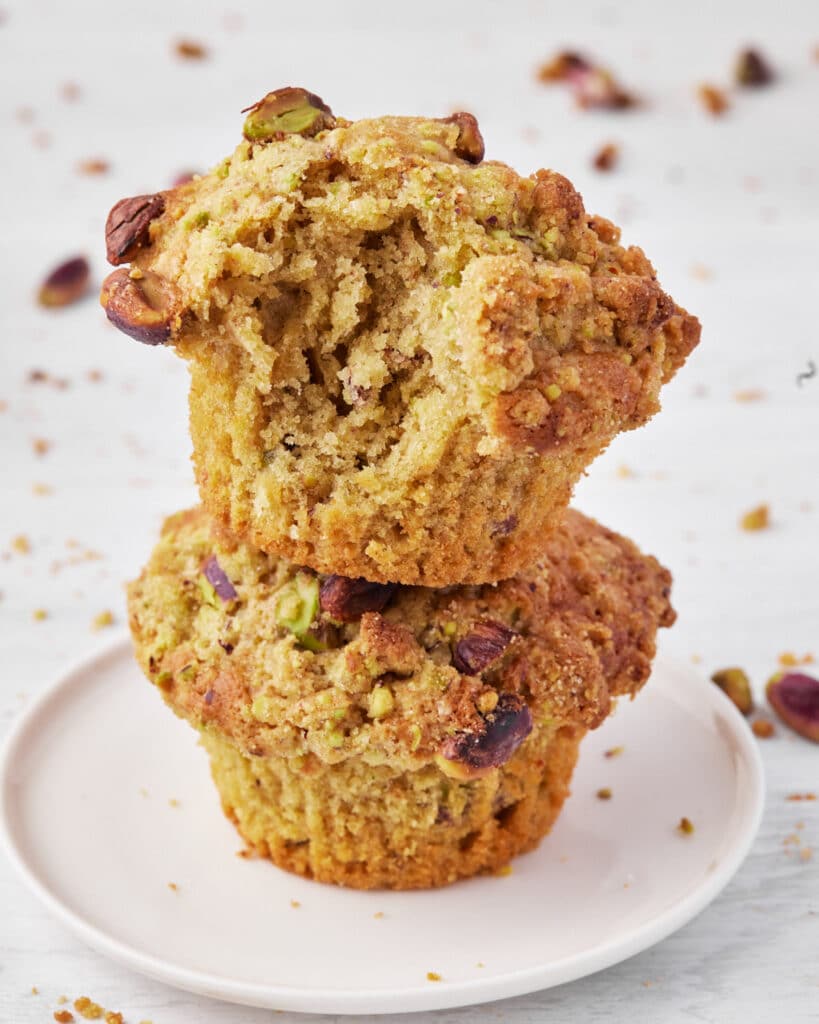 Two stacked pistachio muffins with bite taken out.