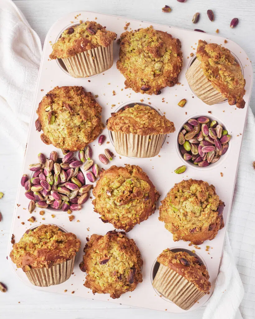Pistachio muffins with pistachio crumble topping in muffin pan.