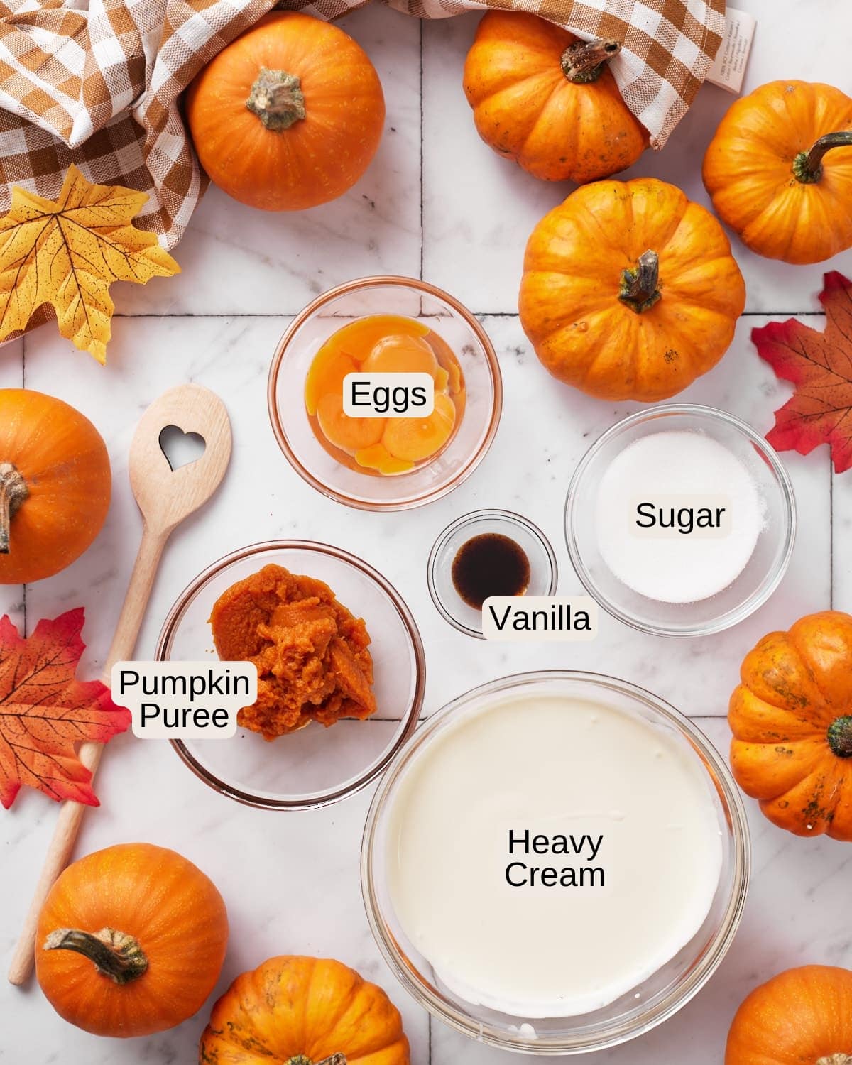 Labelled ingredients for pumpkin creme brûlée, including eggs, sugar, vanilla, pumpkin puree, and heavy cream.