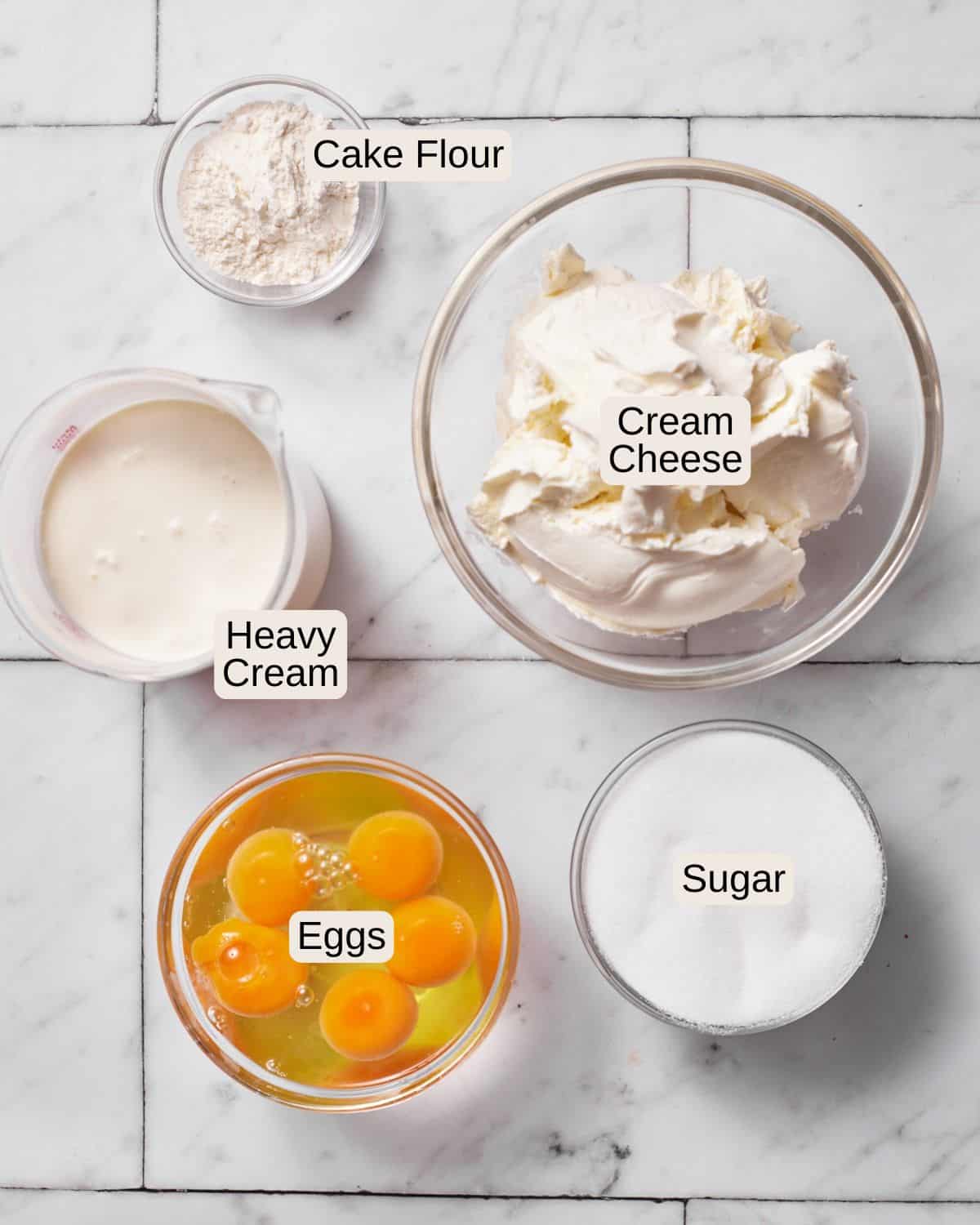 Ingredients to make san sebastian cheesecake, including cake flour, cream cheese, heavy cream, eggs, and sugar.