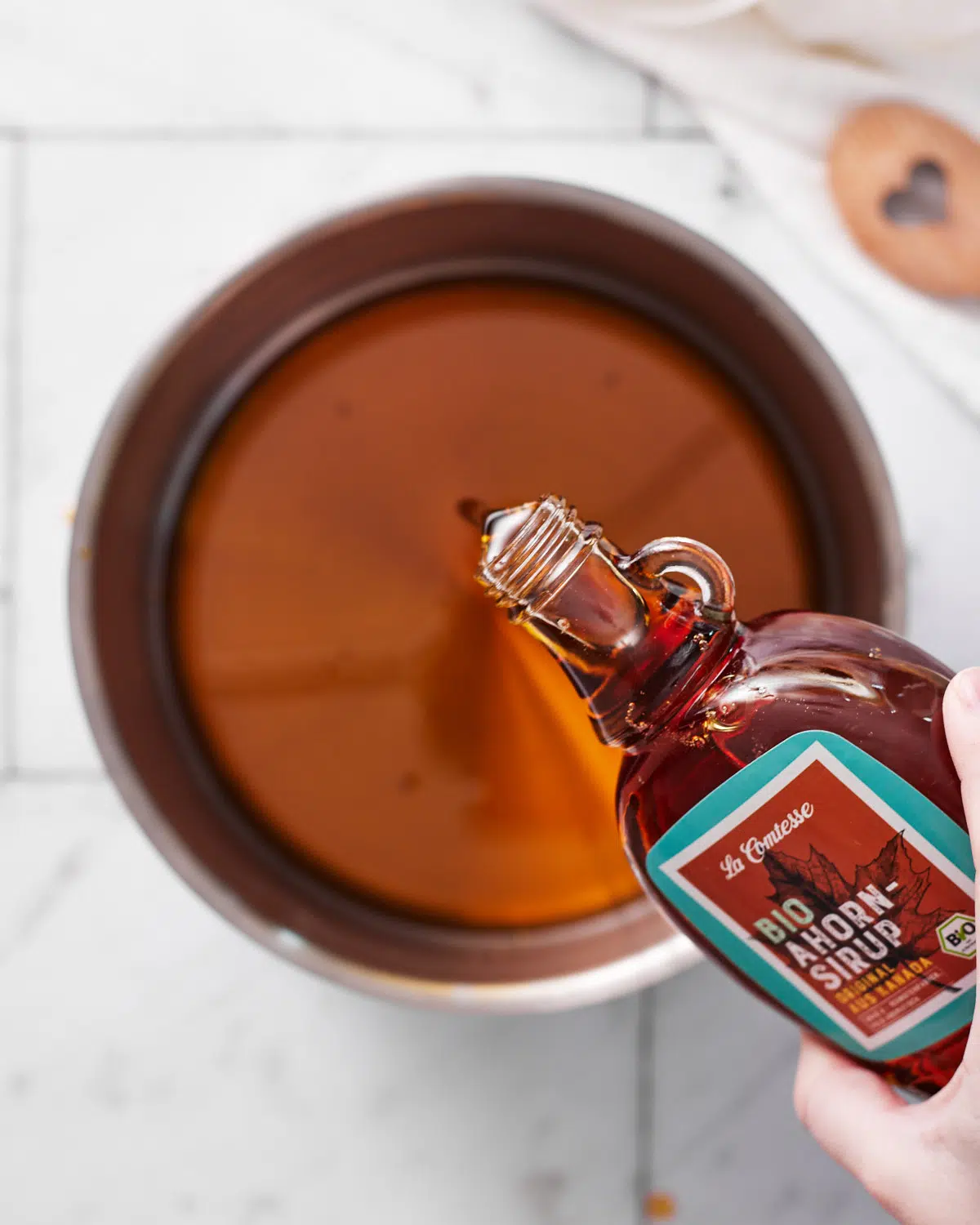 pouring maple syrup into saucepan to make maple cream. 