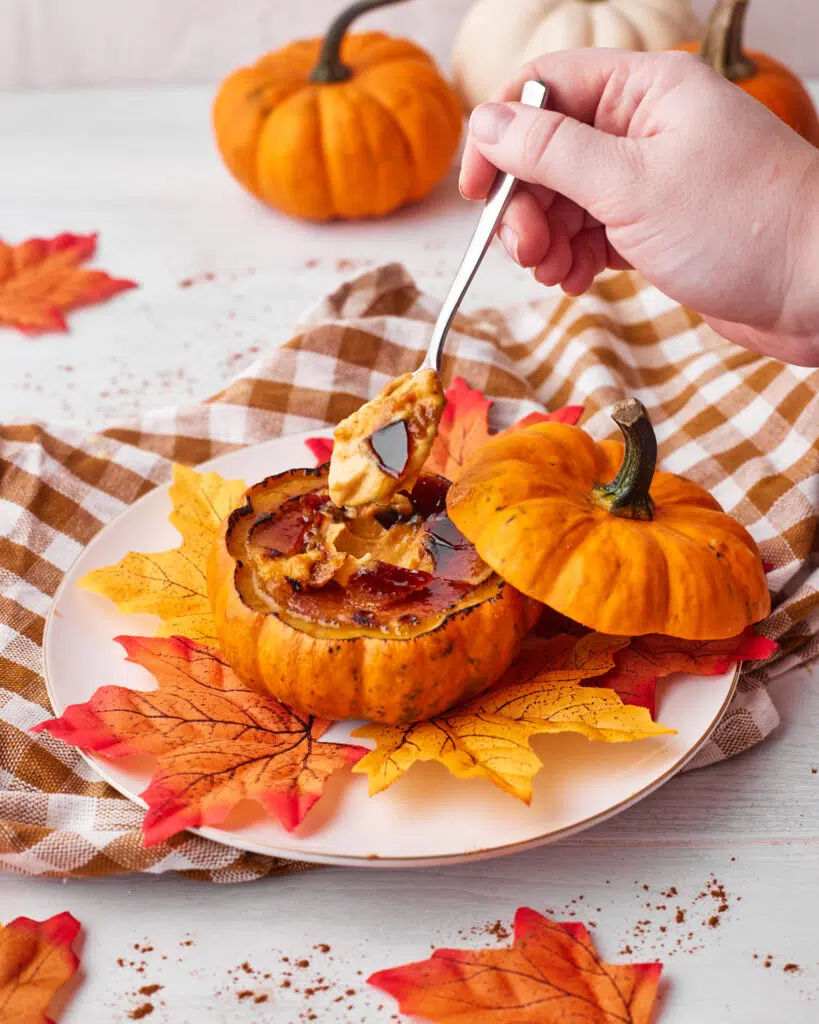 taking a bite of pumpkin creme brulee in a pumpkin.