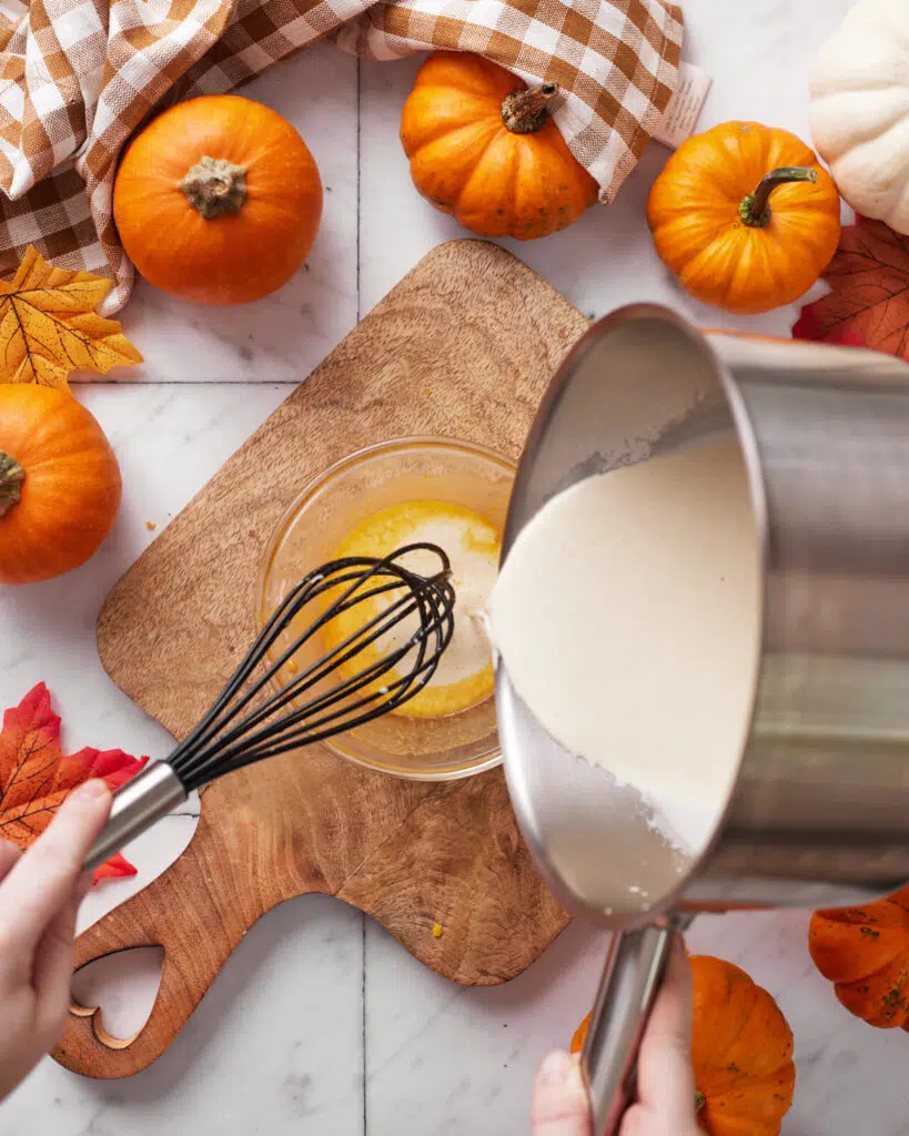 pouring hot cream into eggs for pumpkin creme brulee.