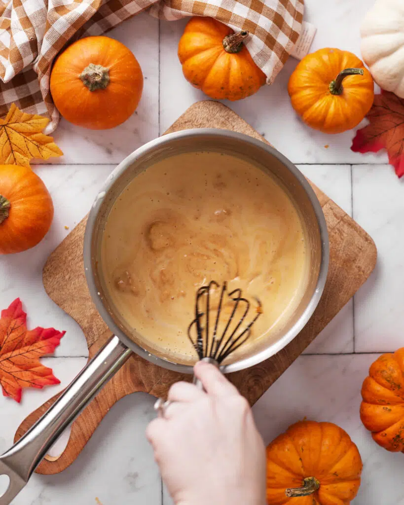 pumpkin creme brulee being whisked in saucepan.