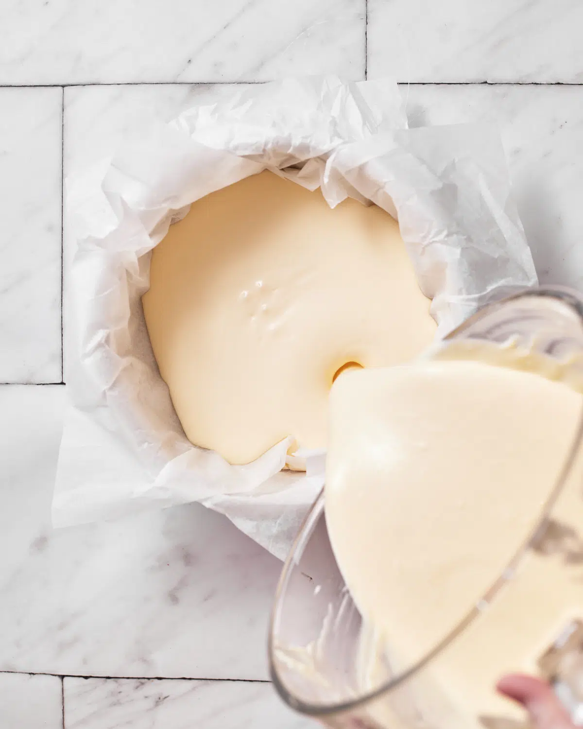 cheesecake batter being poured into cake pan for san sebastian cheesecake. 