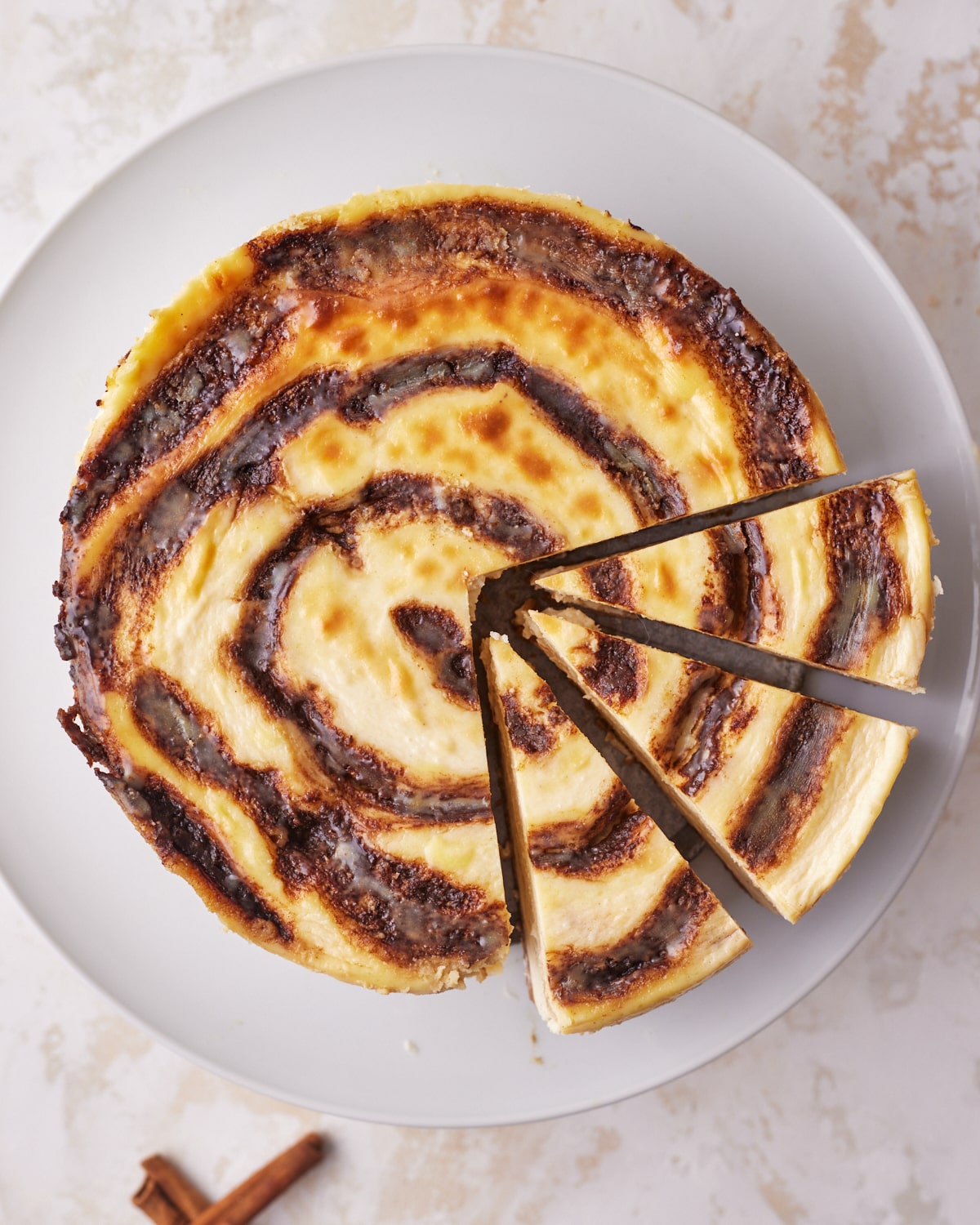 cinnamon roll cheesecake with swirl baked into it with three slices cut out. 